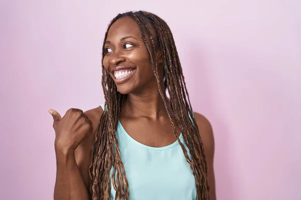Африканская Американка Стоящая Розовом Фоне Улыбаясь Счастливым Лицом Смотрит Указывает — стоковое фото