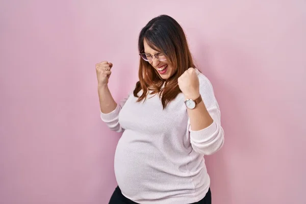 Těhotná Žena Stojící Nad Růžovým Pozadím Velmi Šťastná Nadšená Dělá — Stock fotografie