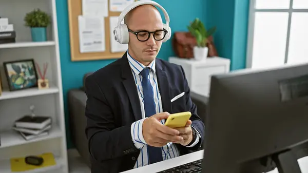 オフィスでスマートフォンやヘッドフォンを使用した若いヒスパニック系男性ビジネスワーカー — ストック写真