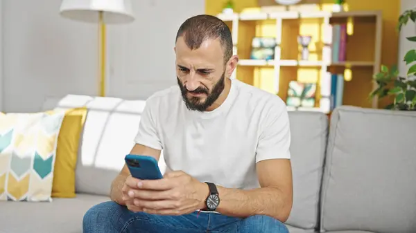 Hombre Hispano Joven Usando Teléfono Inteligente Sentado Sofá Casa —  Fotos de Stock