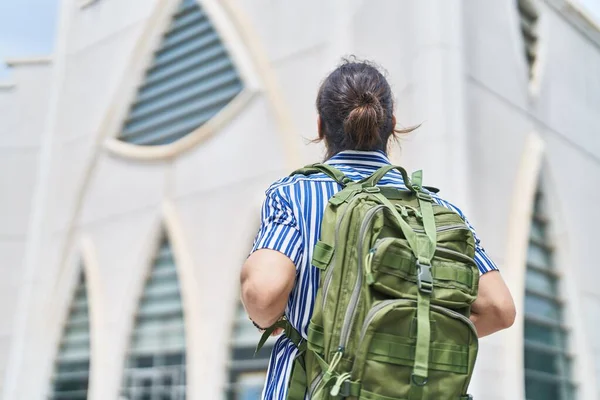 Young hispanic man tourist wearing backpack walking at street