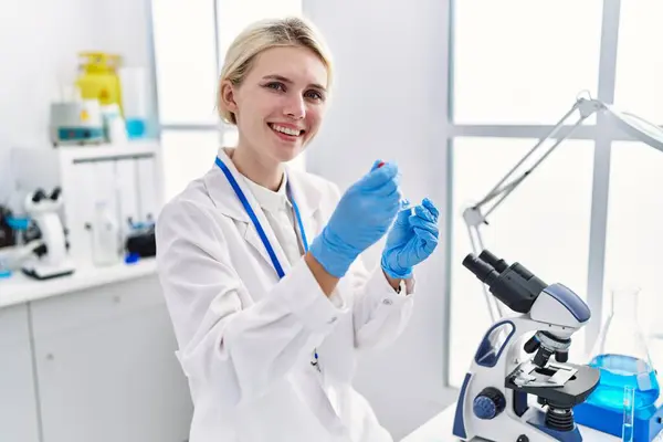 若いブロンド女性科学者注ぎ液体サンプルで実験室 — ストック写真