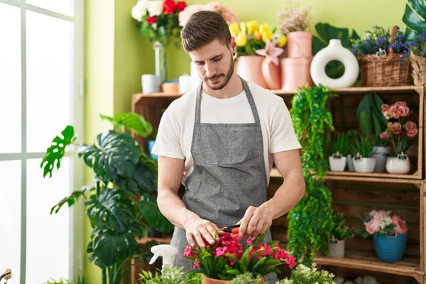 Young caucasian man florist cutting plants at flower shop
