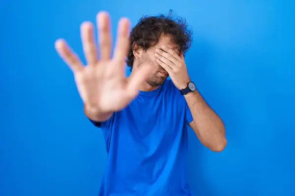 Латиноамериканец Стоящий Синем Фоне Закрывая Глаза Руками Делая Стоп Жест — стоковое фото