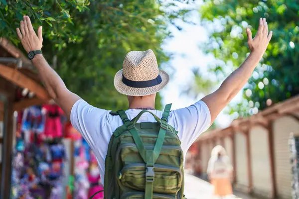 Sokak pazarında kolları açık duran genç beyaz erkek turist.