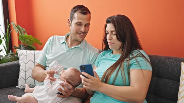 Família Três Bebê Alimentando Sentado Sofá Usando Smartphone Casa — Fotografia de Stock