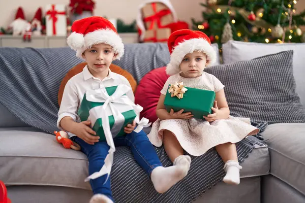 Duas Crianças Segurando Presentes Sentados Sofá Pela Árvore Natal Casa — Fotografia de Stock