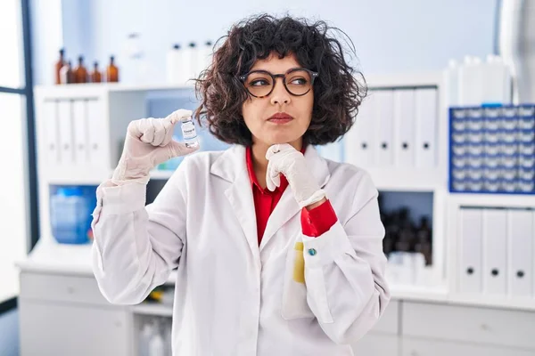 Hispanic Doctor Woman Curly Hair Holding Vaccine Serious Face Thinking — Stock Photo, Image