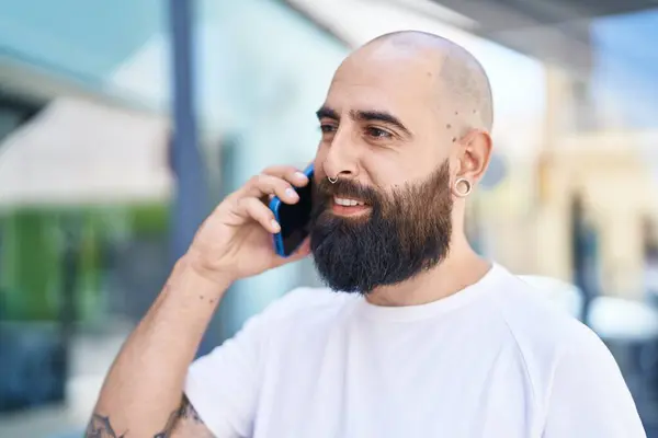 Young bald man smiling confident talking on the smartphone at street