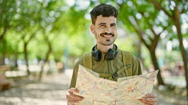 年轻的他的惊慌失措的游客 背着背包和耳机 看着公园的地图 — 图库照片