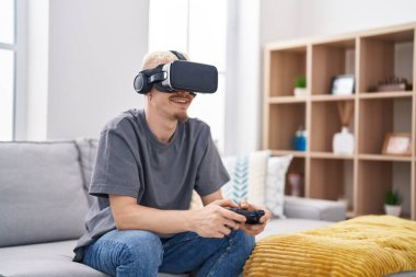 Young caucasian man playing video game using virtual reality glasses at home