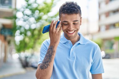 Afro-Amerikalı adam gülümsüyor. Caddedeki akıllı telefondan kendine güvenen bir sesli mesaj dinliyor.