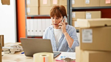 Orta yaşlı kadın ecommerce iş işçisi. Ofiste bilgisayarla konuşuyor.