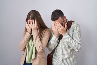 Beyaz arka planda duran genç bir çift. Ağlarken yüzlerini ellerle kapatan üzgün bir ifade. depresyon kavramı. 