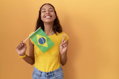 Brezilya bayrağı tutan genç İspanyol kadın umut ve gözleri kapalı gülümseyerek işaret ediyor. Şans ve batıl inançlar. 
