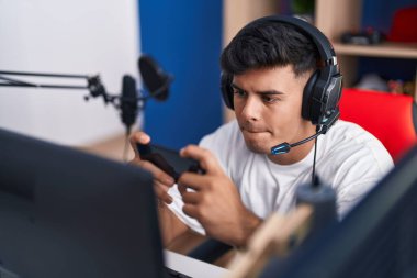 Oyun odasında akıllı telefon kullanarak video oyunu oynayan İspanyol asıllı genç adam.