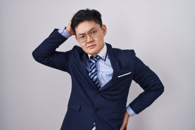 Genç Asyalı takım elbiseli ve kravatlı adam soru sormayı merak ediyor. Şüpheyle kararsız, kafa kafaya düşünerek. Düşünceli kavram. 