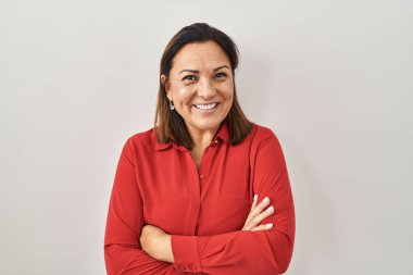 Beyaz arka planda duran, kollarını kavuşturup kameraya gülümseyen Latin kökenli olgun bir kadın. pozitif kişi. 