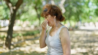 Parkta polen alerjisi olan orta yaşlı bir kadın.