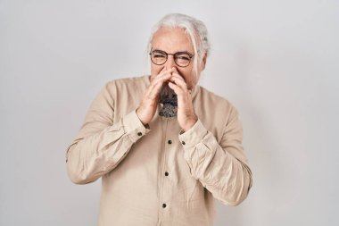 İzole edilmiş arka planda duran gri saçlı orta yaşlı bir adam pis ve iğrenç bir koku alıyor. Dayanılmaz bir koku. Parmakları burnunda nefesini tutuyor. Kötü kokuyor. 