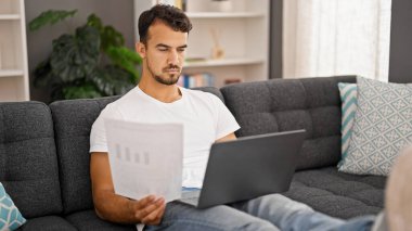 Genç İspanyol adam evde bilgisayar kağıdı kullanıyor.