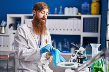 Laboratuvarda eldiven takan kızıl saçlı genç bilim adamı.