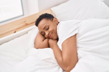 Afro-Amerikalı kadın yatakta uzanıyor. Yatak odasında uyuyor.