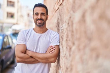 Genç İspanyol adam gülümsüyor. Kendine güveni tam. Sokakta çapraz hareketlerle duruyor.