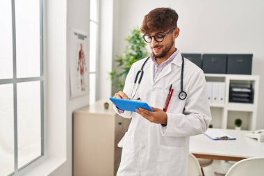 Young arab man wearing doctor uniform using touchpad working at clinic