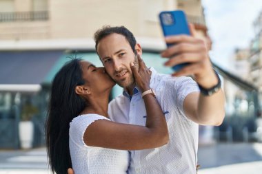 Man and woman interracial couple making selfie by smartphone at street