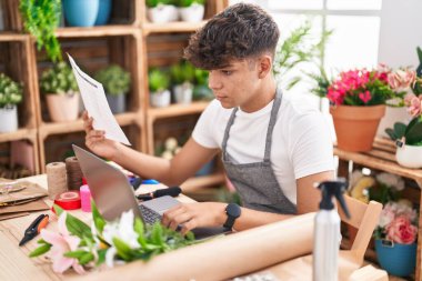 Çiçekçide dizüstü bilgisayar okuyan genç İspanyol çiçekçi.