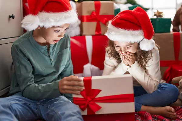 Двое Детей Распаковывают Подарок Сидя Дома Полу Новогодней Елки — стоковое фото