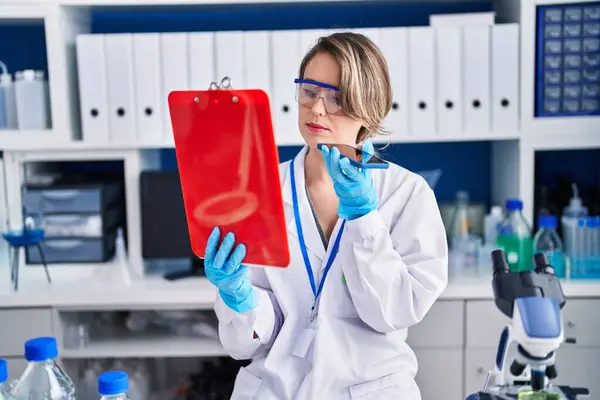 Young woman scientist reading report talking on smartphone at laboratory