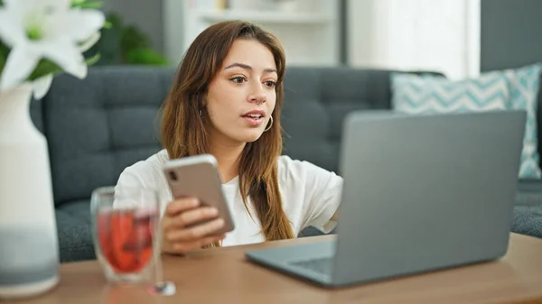 年轻美丽的惊慌失措的女人坐在家里的地板上 用笔记本电脑和智能手机 — 图库照片