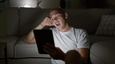 Evde yorgun, dokunmatik ped kullanan genç bir İspanyol.