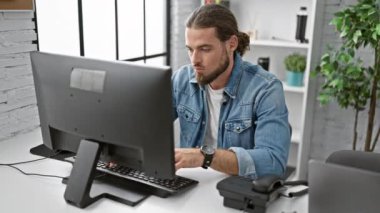 Genç İspanyol iş adamı telefonda konuşuyor. Ofiste bilgisayar kullanıyor.