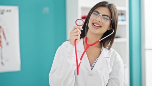 Joven Mujer Caucásica Doctora Sonriendo Confiada Sosteniendo Estetoscopio Clínica — Vídeos de Stock