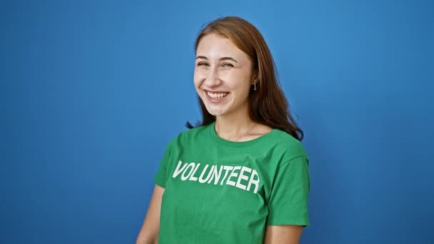Genç Bayan Gönüllü Mavi Arka Planda Gülümseyen Kameraya Işaret Ediyor — Stok video