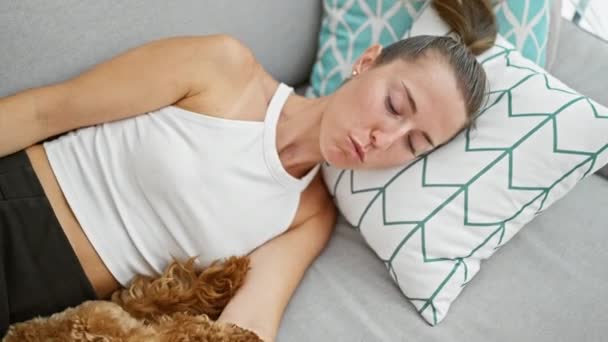 自宅で一緒にソファーに横たわっている犬を持つ若い白人女性 — ストック動画