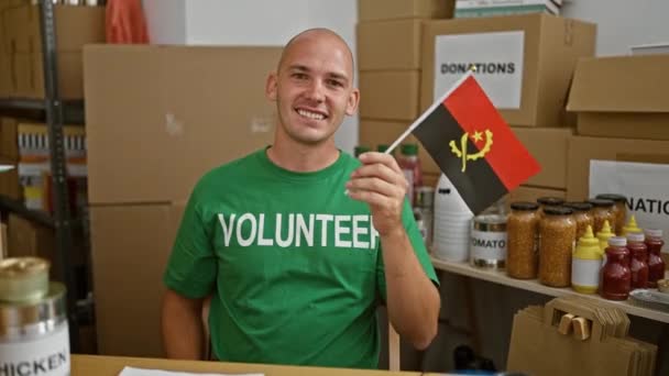 Jovem Hispânico Voluntário Sorrindo Confiante Segurando Bandeira Angola Centro Caridade — Vídeo de Stock