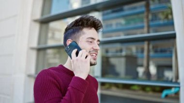 Genç İspanyol adam gülümsüyor. Kendine güveniyor. Sokakta akıllı telefondan konuşuyor.