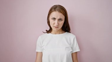 Genç bir kadın pembe arka planda baş parmağıyla negatif işaret veriyor.