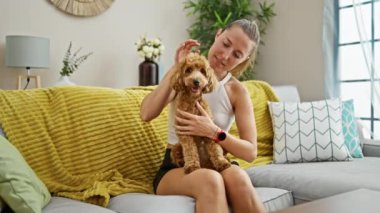 Köpekli beyaz bir kadın evdeki kanepede oturuyor.