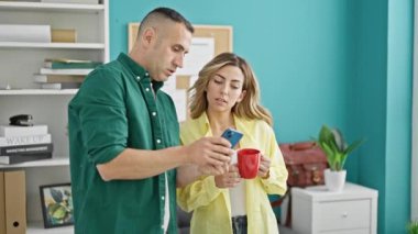 Kadın ve erkek işçiler ofiste çalışırken laptoplarını içip kahve içiyorlar.