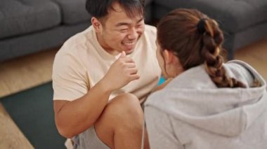 Erkek ve kadın çift gülümseyerek evde kendilerine güvenen karın kasları egzersizi yapıyor.