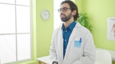 Klinikte steteskop takmış, ciddi bir ifadeyle duran genç İspanyol doktor.