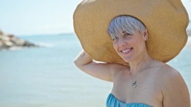 Bikini giyen ve plajda gülümseyen genç bir kadın turist.