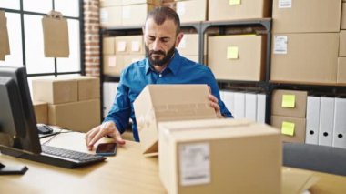 Genç İspanyol adam ecommerce iş çalışanı Ofiste akıllı telefon ile paket tarama