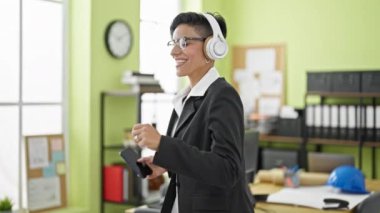 Genç, güzel İspanyol kadın iş adamı ofiste dans eden müzik dinliyor.