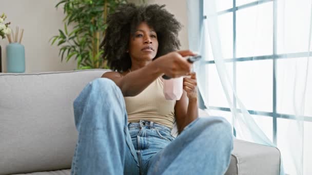 Femeie Afro Americană Care Uită Televizor Consumând Cafea Acasă — Videoclip de stoc